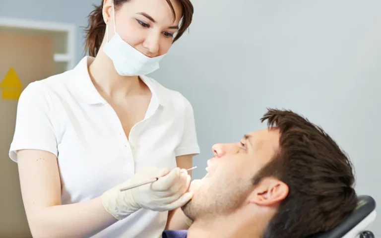 A person sitting in a dental chair while a dentist examines their teeth.